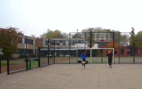 Leerlingen voetballen en basketballen op het schoolplein.