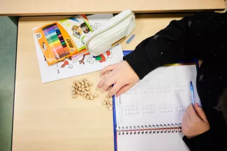 Handen van leerling die in het klaslokaal werkt met blokjes en tellen.